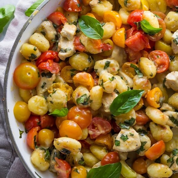 overhead shot of caprese gnocchi skillet with basil in large white skillet