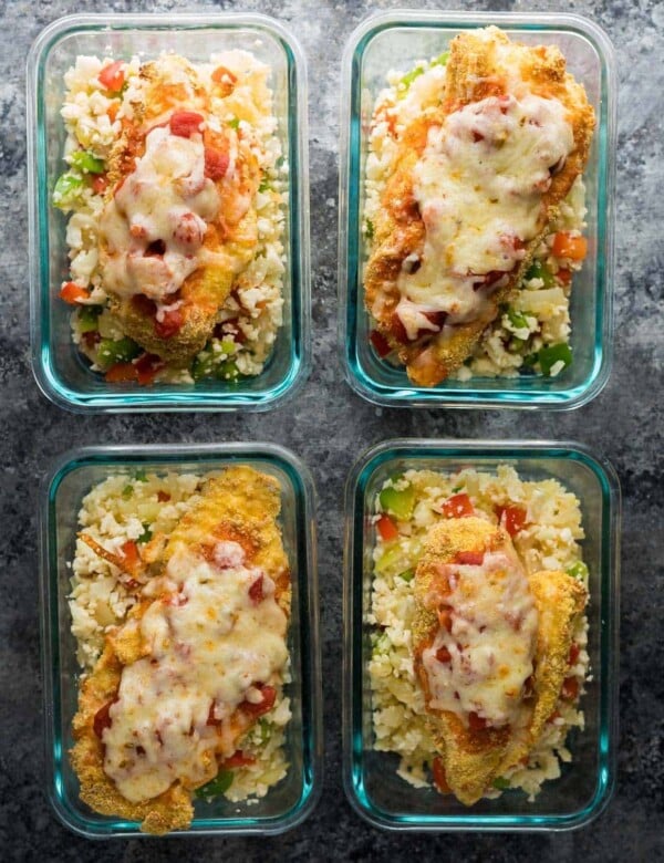 overhead shot of four glass containers with mexican chicken cauliflower rice meal prep bowls