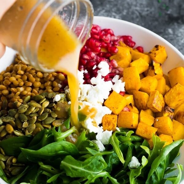 salad dressing being poured over harvest lentil salad