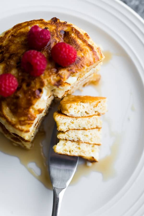 stack of homemade fluffy pancakes with slice out of it from above, and bite shot on fork