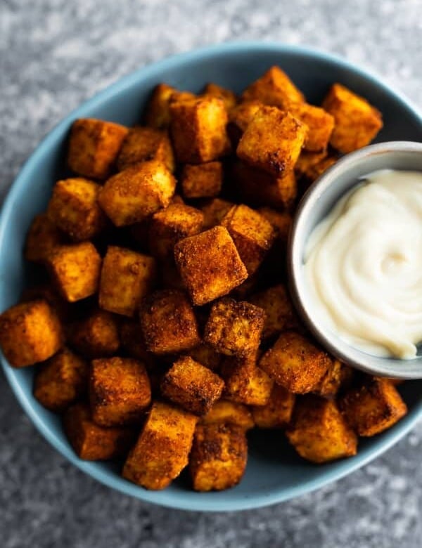 A blue bowl filled with crispy air fryer tofu and dipping sauce