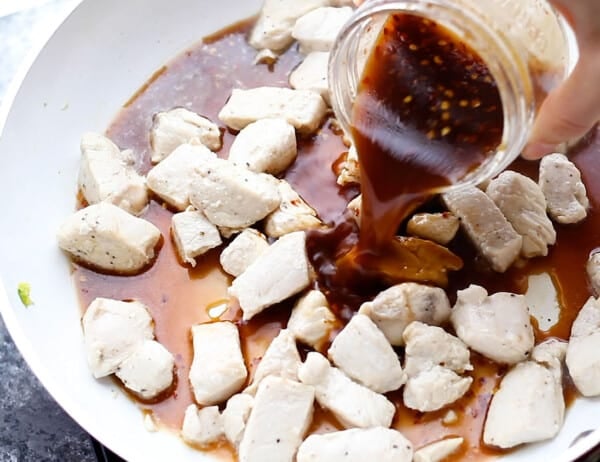 adding sauce to chicken in frying pan