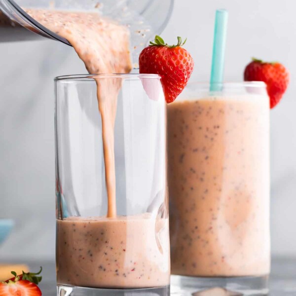 pouring strawberry smoothie out of blender into glass